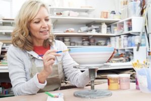 middle-aged woman painting a ceramic bowl