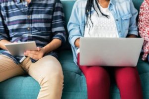 man and woman on a couch using a tablet and a laptop